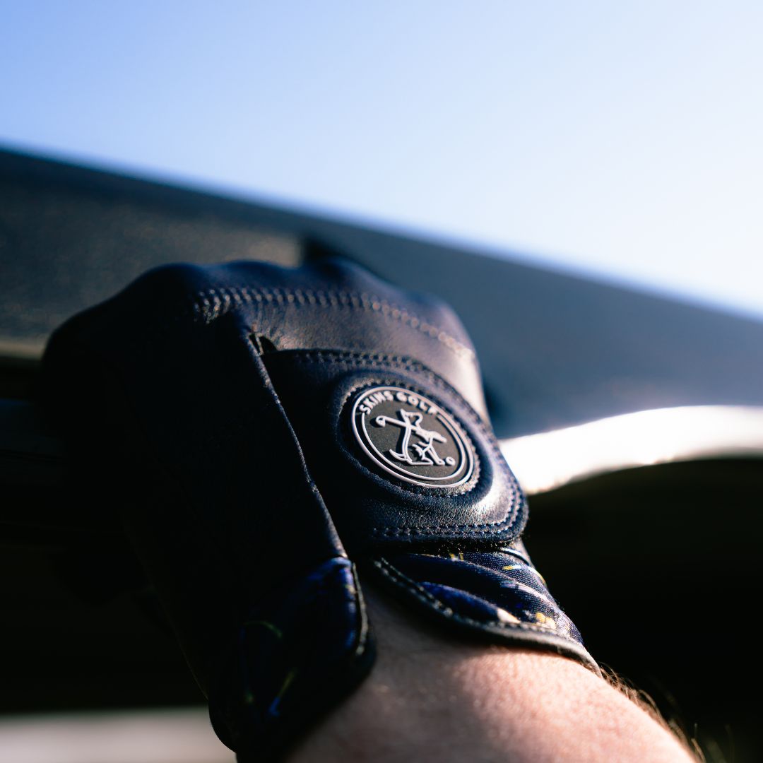 Close-up of a person wearing a navy glove with a logo on a blurred background