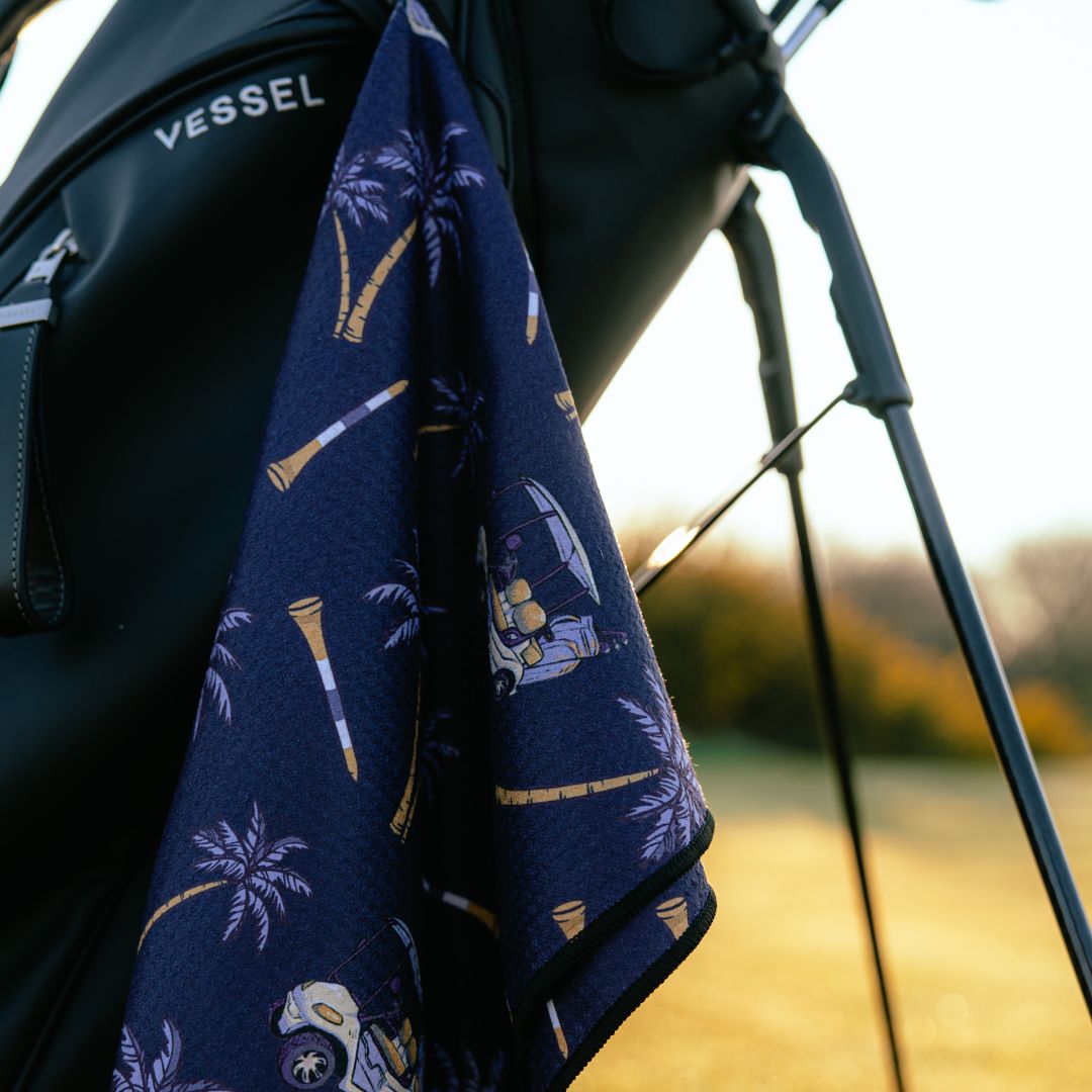 Navy blue towel with gold and white designs draped over a golf bag.