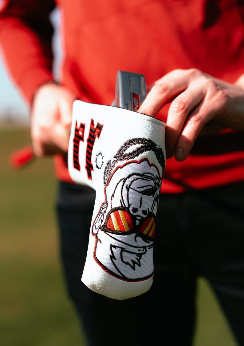 Golf club head cover with gorilla design held by a person in a red shirt on a grassy background
