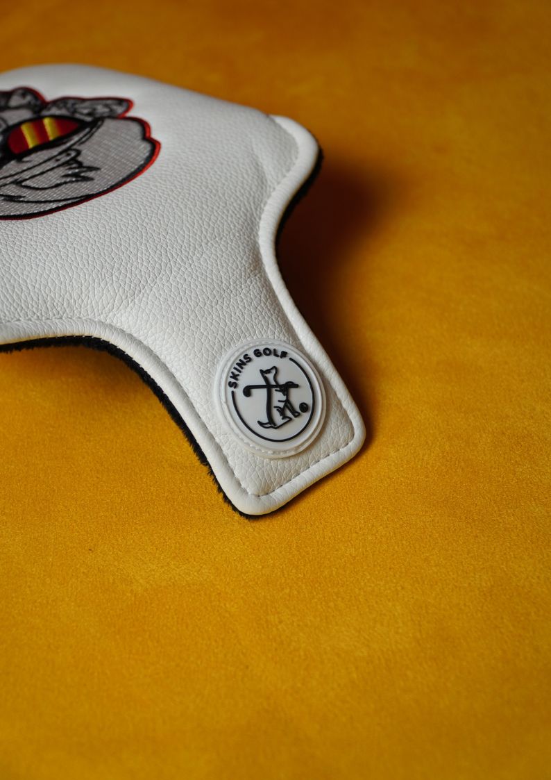 White golf club head cover with a logo on a yellow background