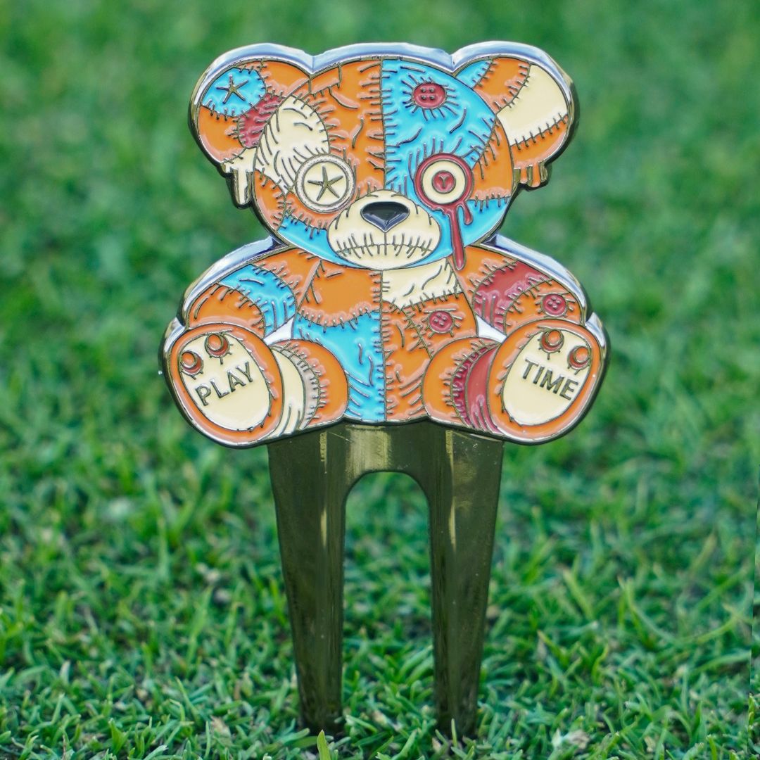 Colorful voodoo bear-shaped pitch mark repairer on grass