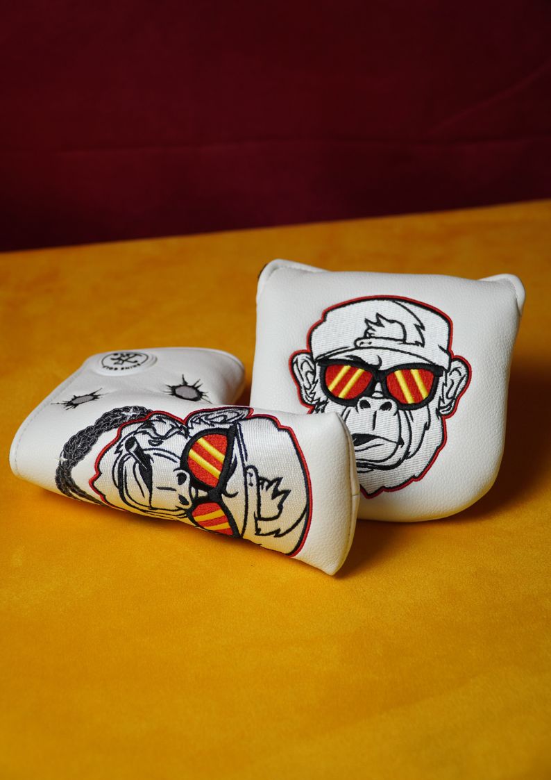 Two decorative golf putter headcovers with gorilla designs on a yellow surface.