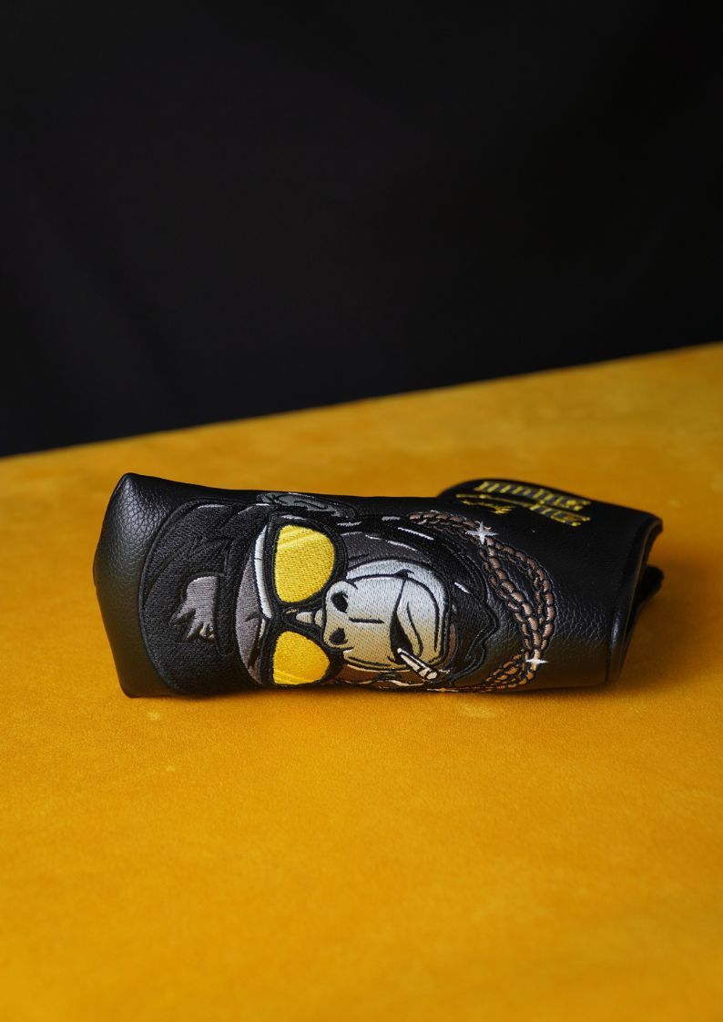 Black leather golf club head cover with gorilla design on a yellow surface