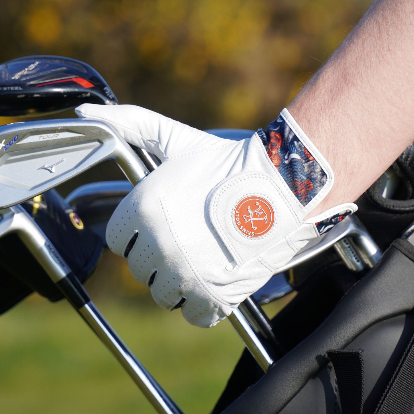 Golf club with a gloved hand on a blurred golf course background