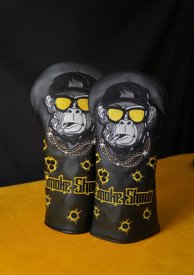 Two golf club head covers with monkey design and 'Smoke Show' branding on a black background.