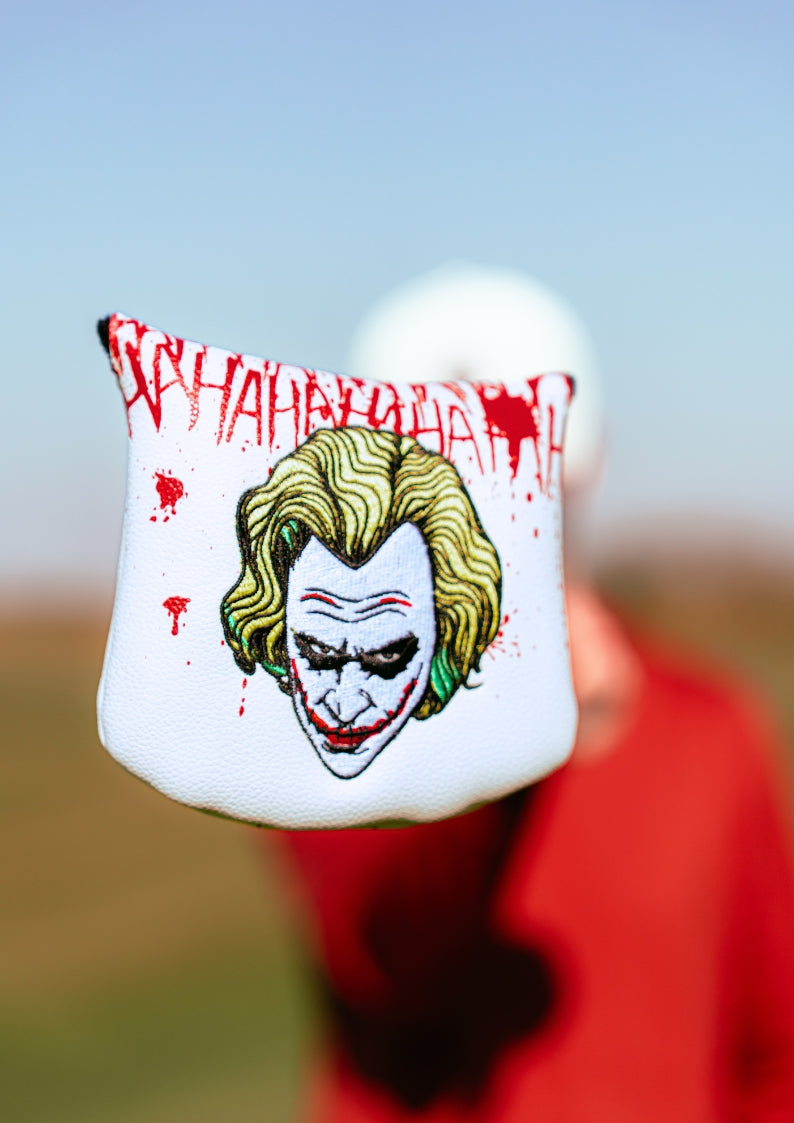 Golf club head cover with Joker design and text on a blurred background