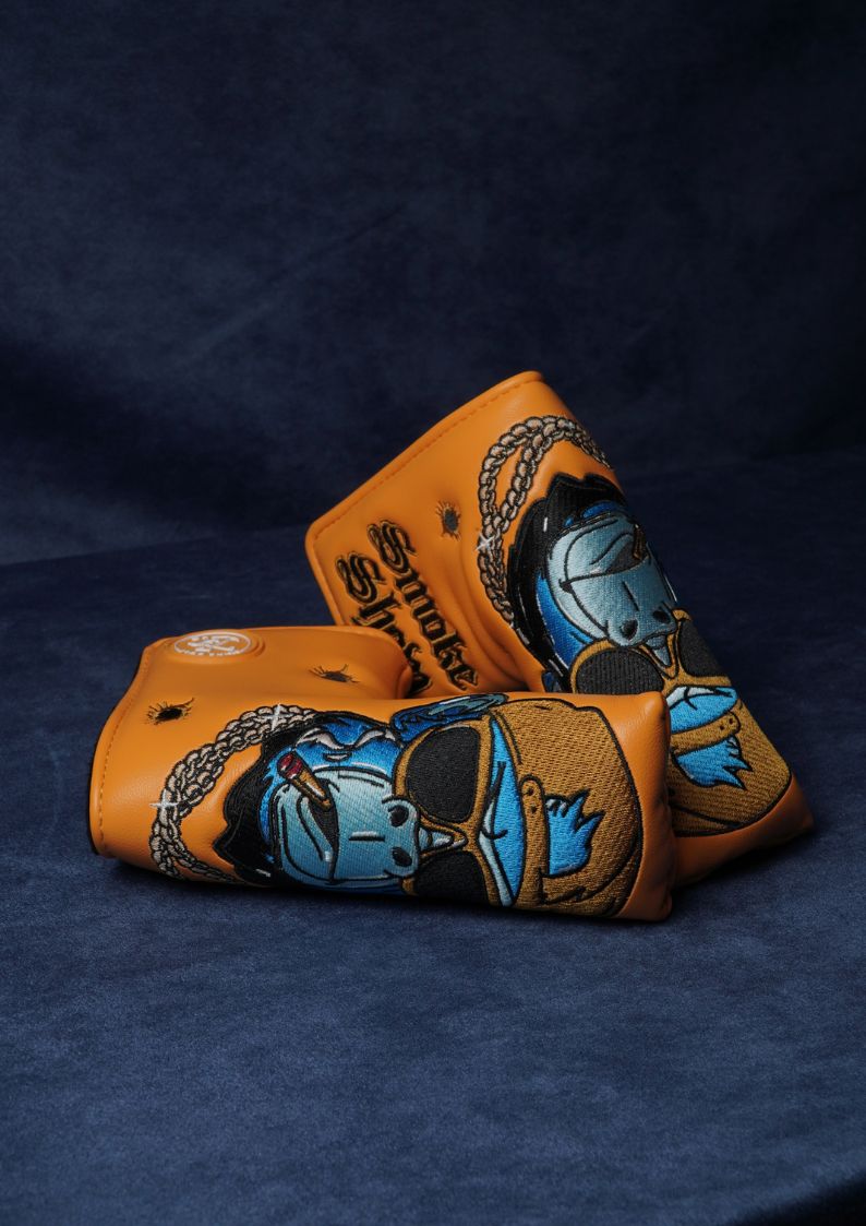 Two leather golf club covers with artistic designs on a dark blue background