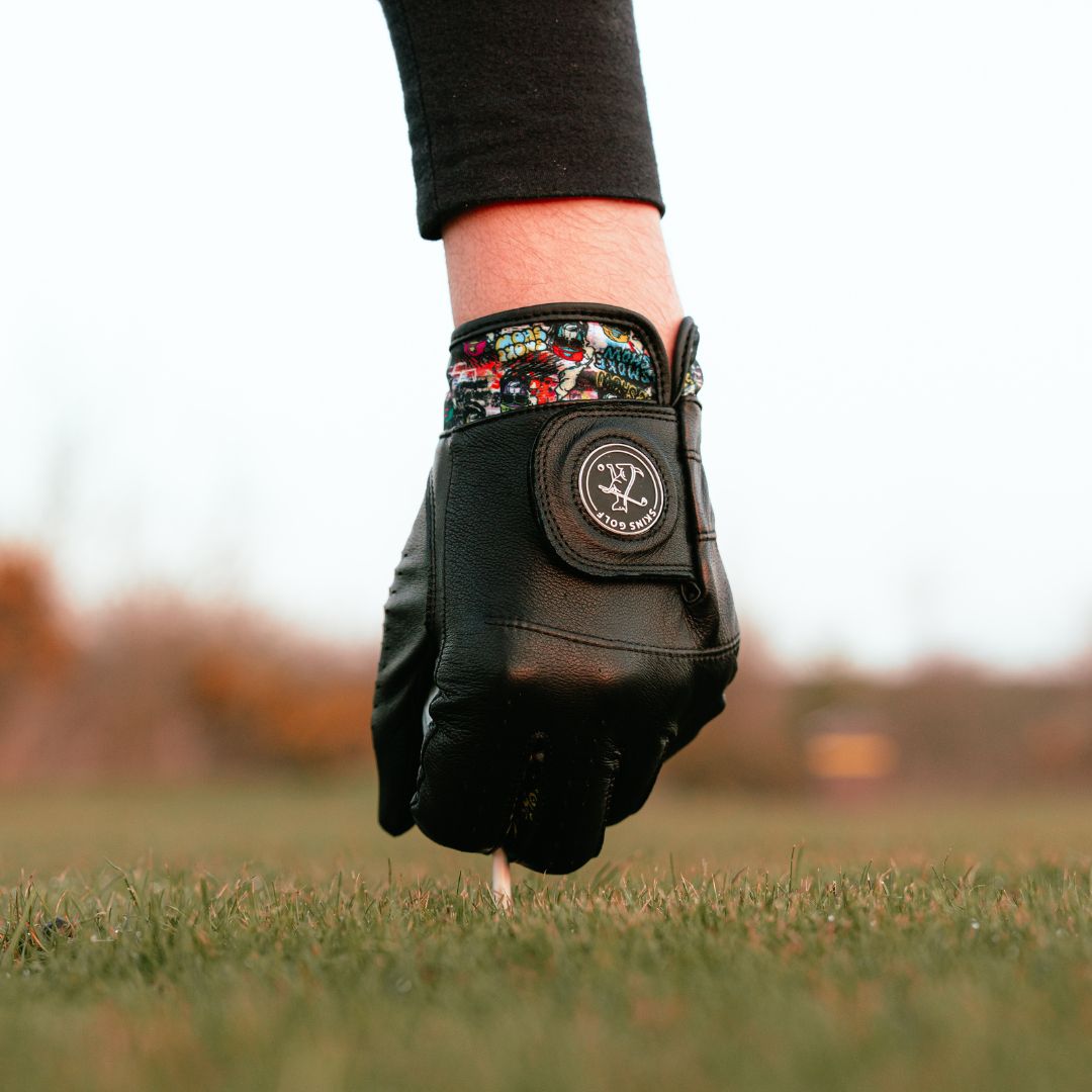 teeing up golf ball with black golf glove