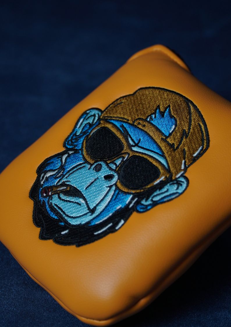 Orange golf headcover with a blue and brown gorilla design wearing sunglasses on a dark blue background