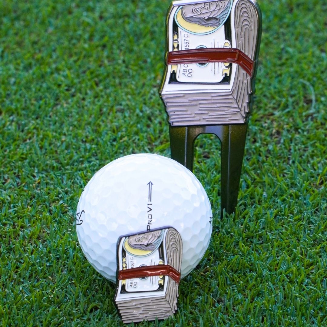 Golf ball with money ball marker on grass