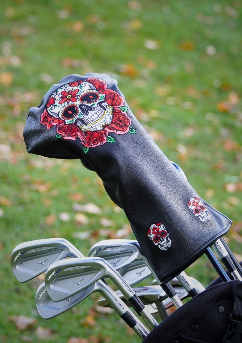 Golf club head cover with skull and rose design on a grass background