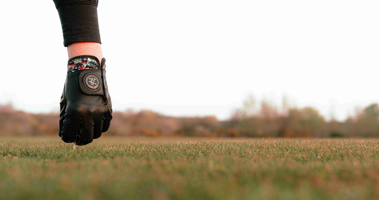 Black leather golf glove teeing up ball