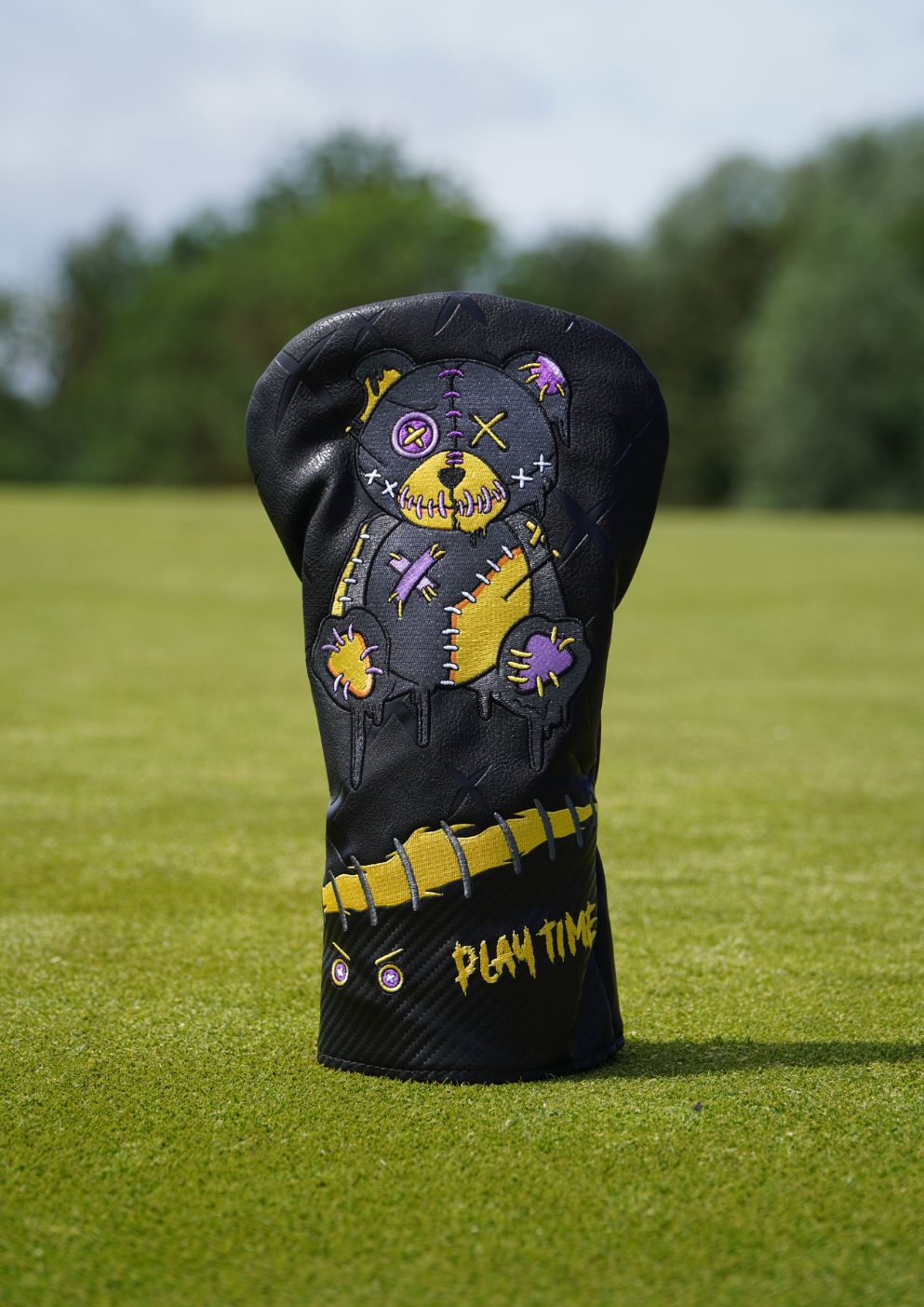 Golf club head cover with colorful design on a grassy background