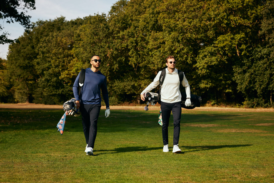 Golfers wearing golf hoodie walking down fairway