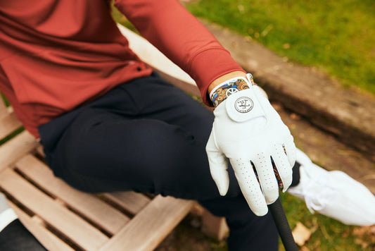 Golfer sitting on a bench wearing golf glove