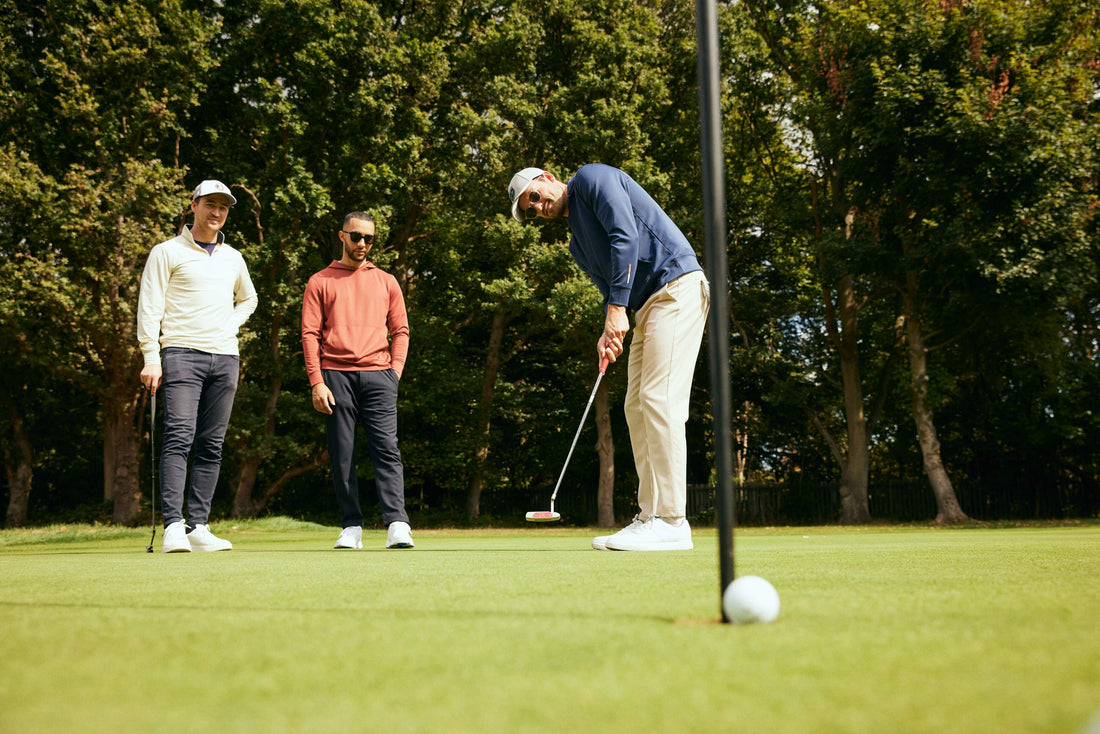 Golfer wearing a hoodie taking a putt