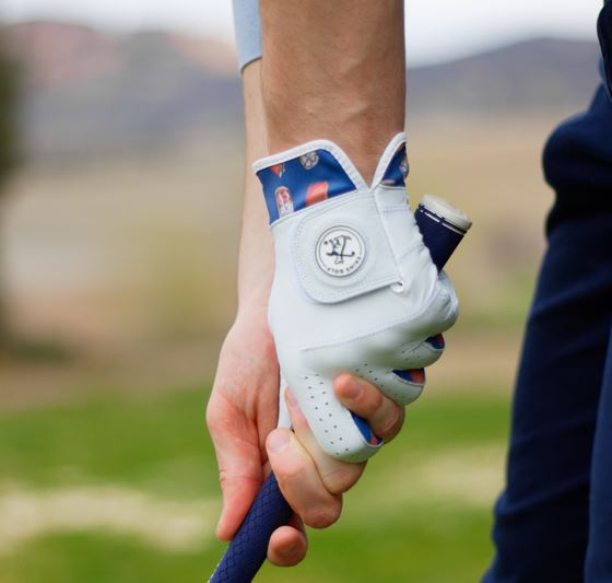 Golfer holding club with whiskey themed white golf glove