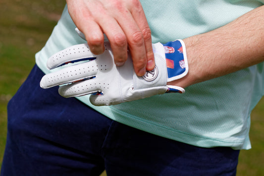 Golfer putting on white and blue golf glove