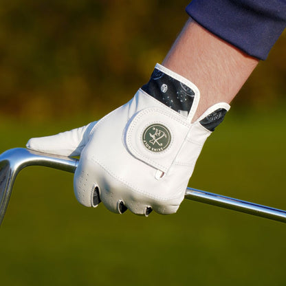 Close-up of a person's hand wearing a white golf glove holding a golf club on a blurred green background