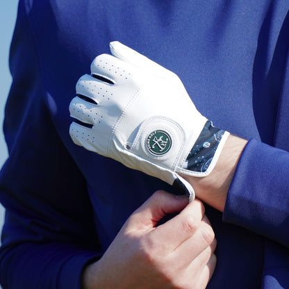 White golf glove with a brand logo being worn on a person's hand against a blue background