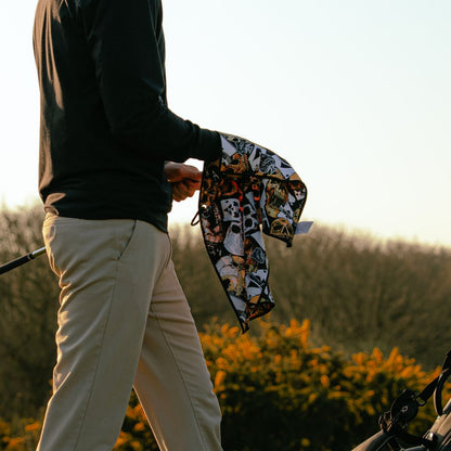 Person holding a colourful golf towel with a scenic background