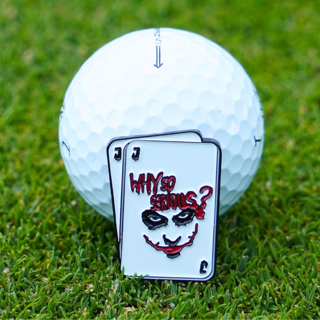 Joker themed golf ball marker laying on a golf ball