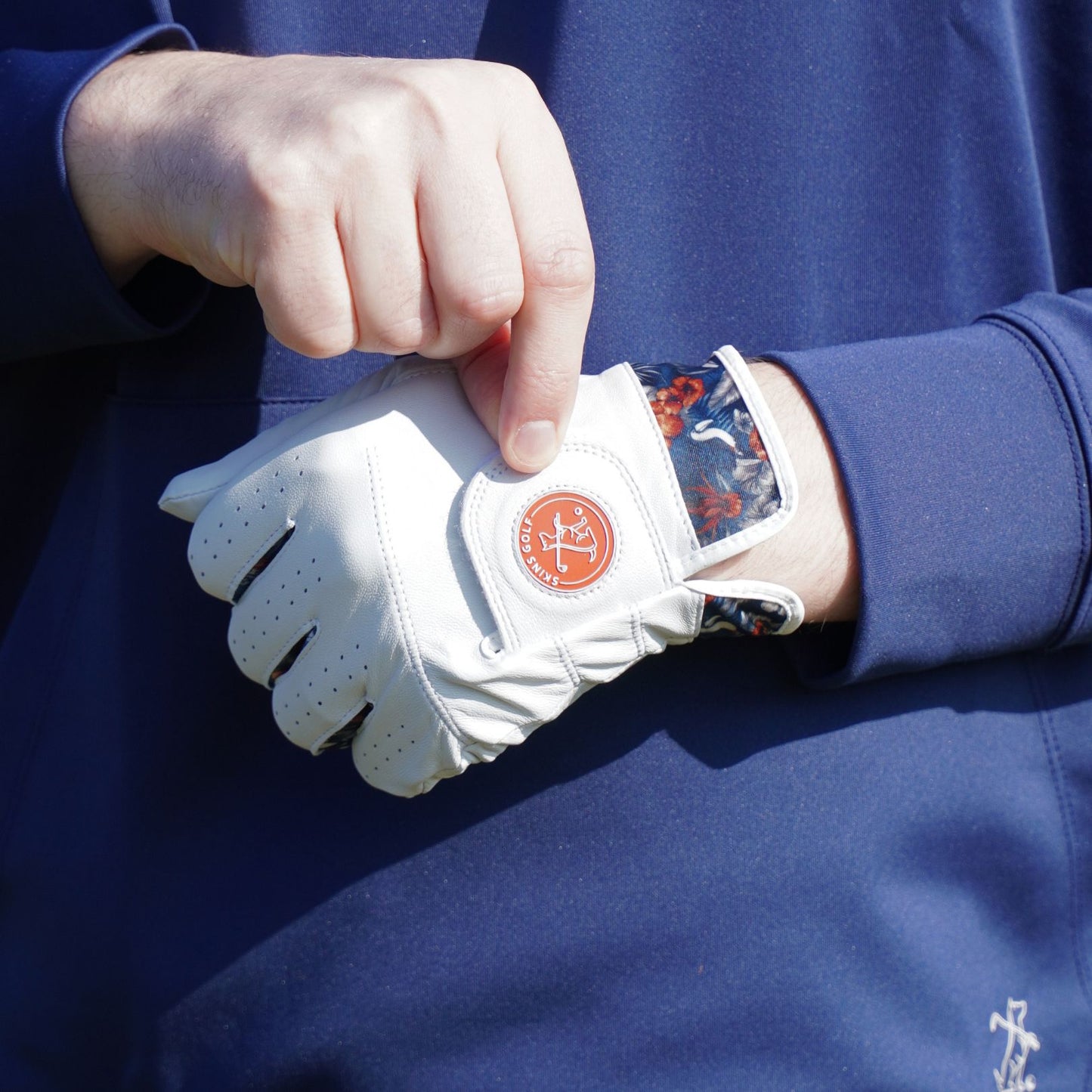 Person wearing a white glove with a logo on a blue background