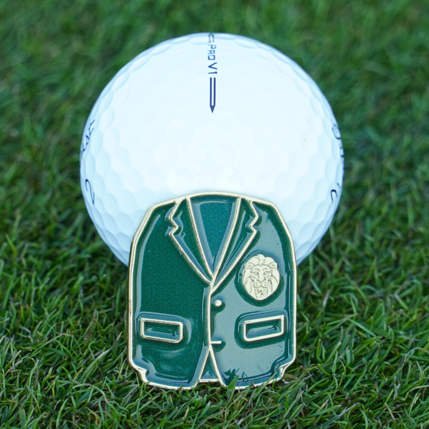 Golf ball with a green blazer ball marker on grass