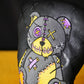 Voodoo bear with yellow and purple accents on golf headcover on a black background