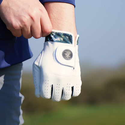 White golf glove held by a person on a blurred outdoor background