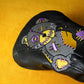 Black driver headcover with colorful patch design on a yellow background