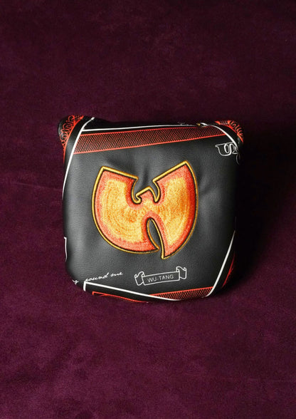 A black leather golf club headcover featuring the Wu-Tang Clan logo in orange and yellow, with white piping and text, displayed on a dark purple textured background.