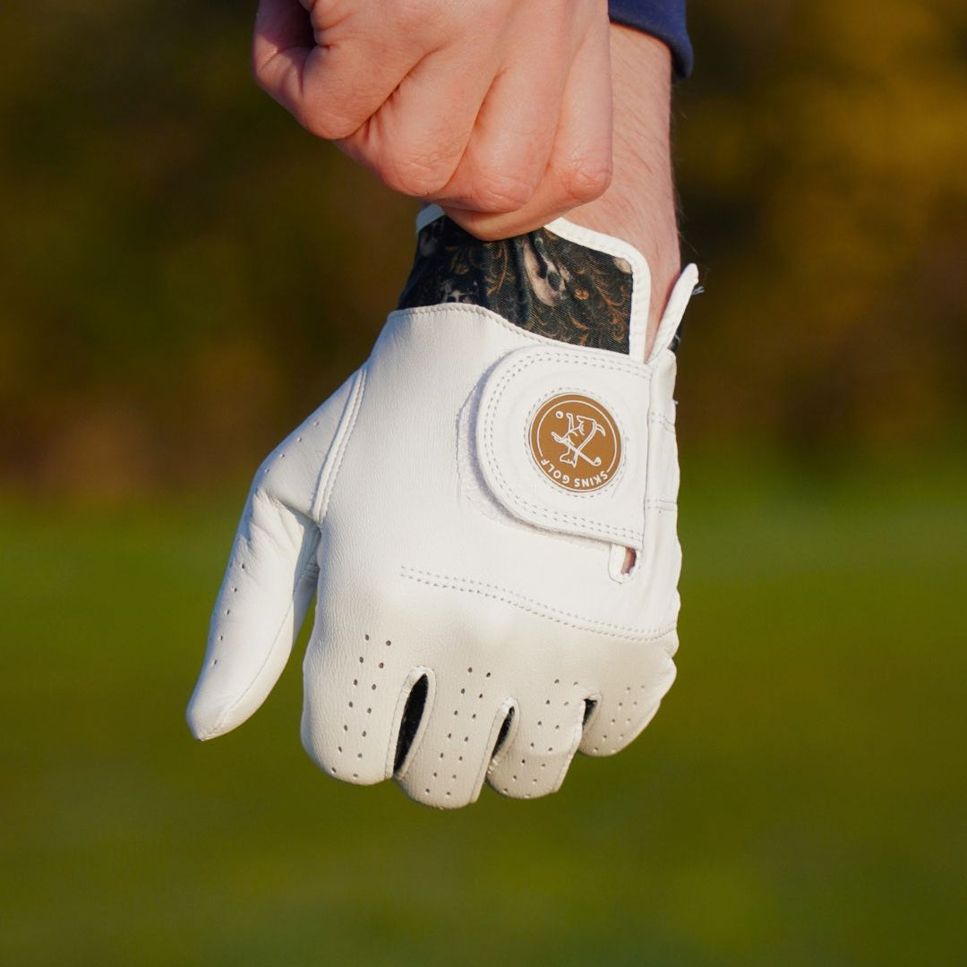 White golf glove held by a person on a blurred green background