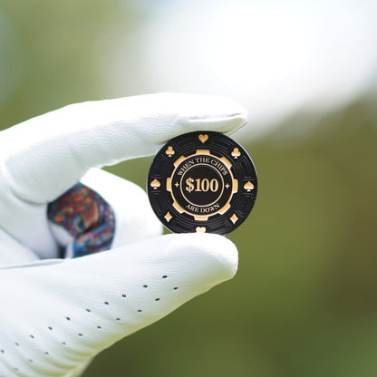 Black $100 poker chip held in a white glove with a blurred background