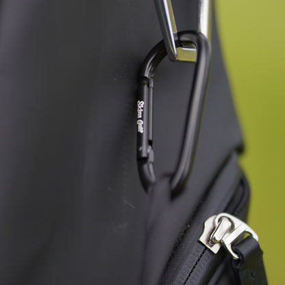 Close-up of a black bag with a carabiner and zipper detail on a green background