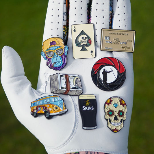White glove with various colorful golf ball markers on a green background