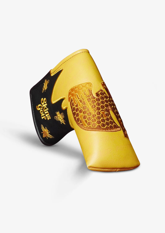 A yellow and black golf club cover featuring a gold honeycomb pattern and bee designs, with the text 'Skins Golf' printed on the black section.