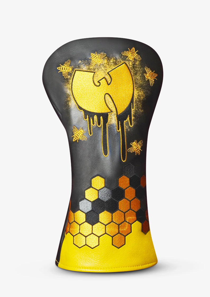 A golf club headcover featuring a black and yellow design with a dripping gold Wu-Tang Clan-style logo, gold bees, and a honeycomb pattern in yellow, orange, and gray at the bottom, shown on a light gray background.
