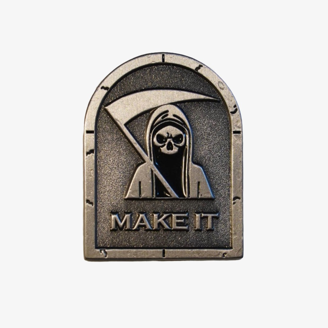 Decorative golf ball marker with a hooded figure and 'MAKE IT' text on a white background