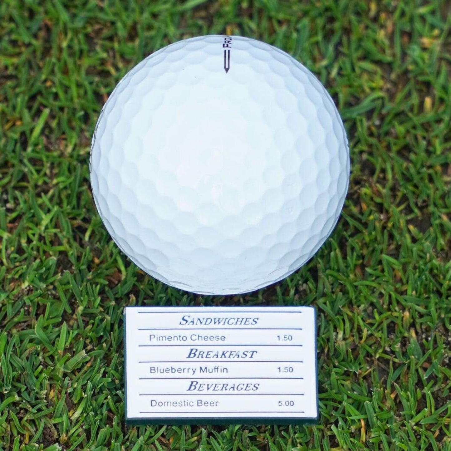 Golf ball on grass with a menu ball marker below