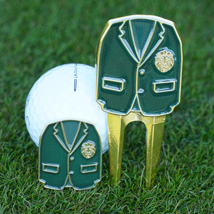 Golf ball with a green jacket and gold club ball marker and divot tool on grass