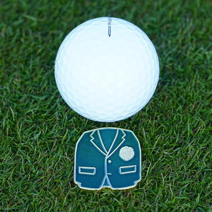 White golf ball on grass with a green jacket ball marker 