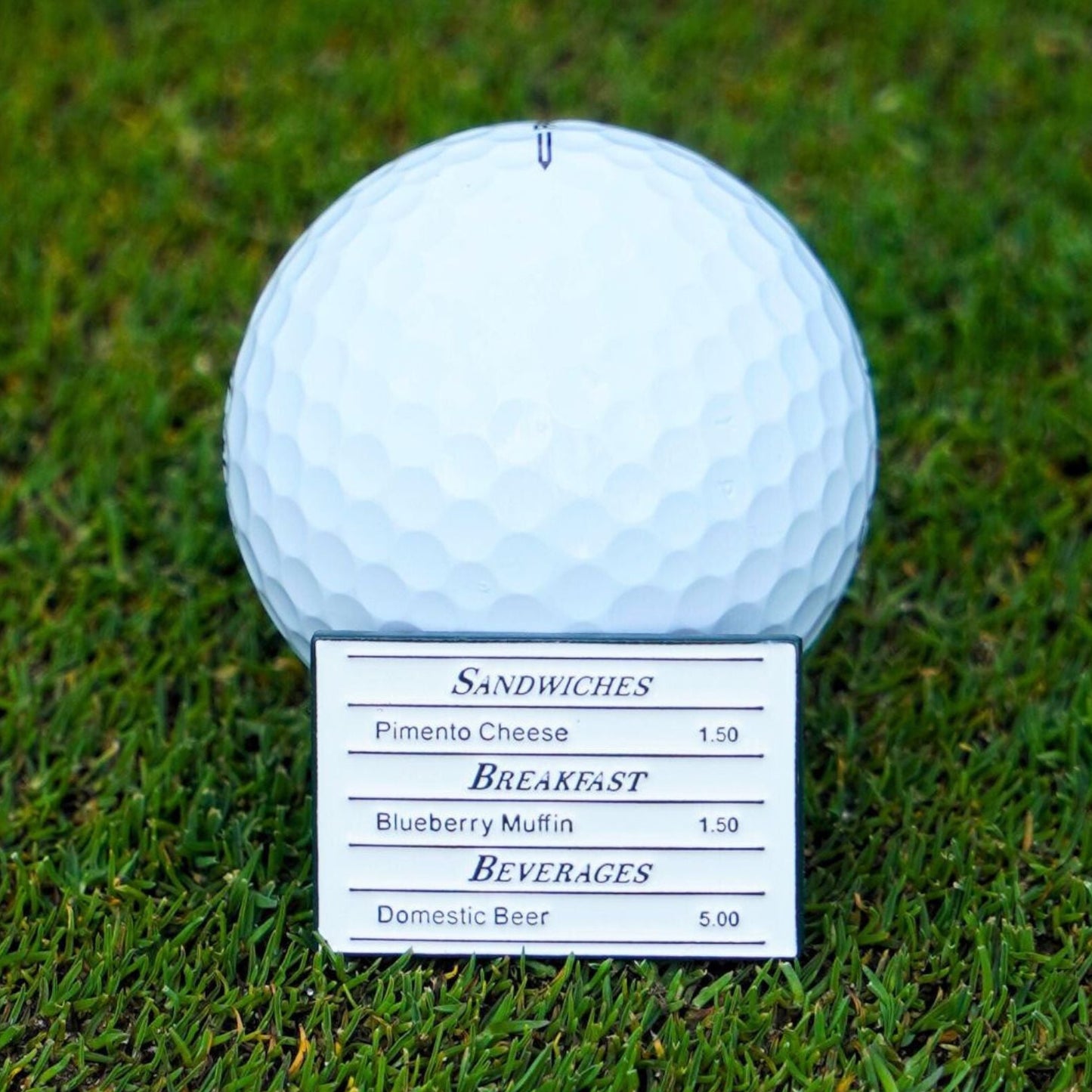 Golf ball marker with a menu card on grass