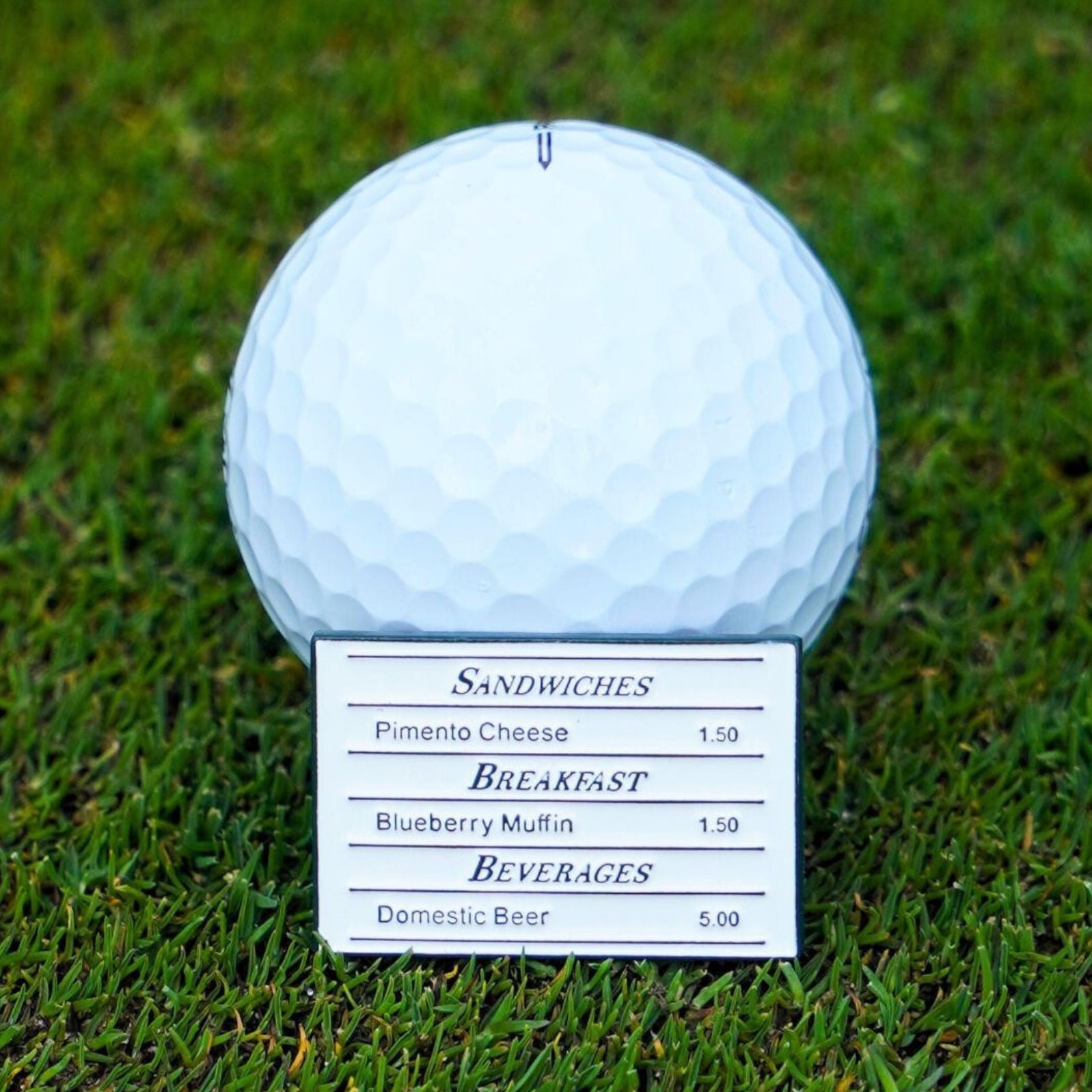 Golf ball marker with a menu card on grass