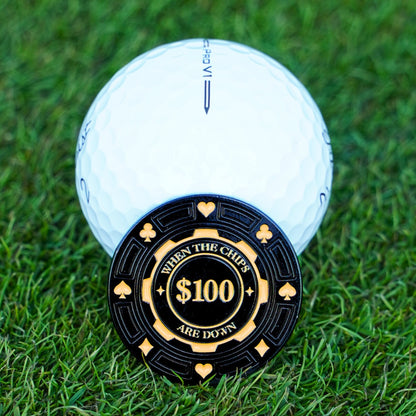 Golf ball with a $100 poker chip on grass