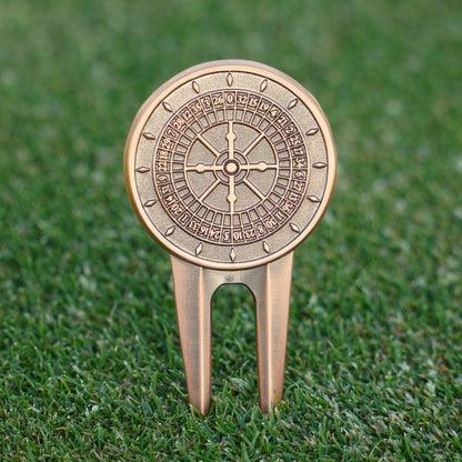 Decorative golf divot tool with roulette design on a grass background