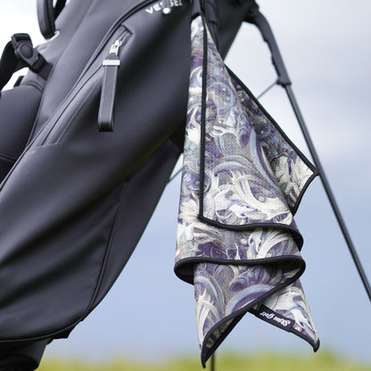 Golf towel with paisley pattern draped over a golf bag against a blurred background
