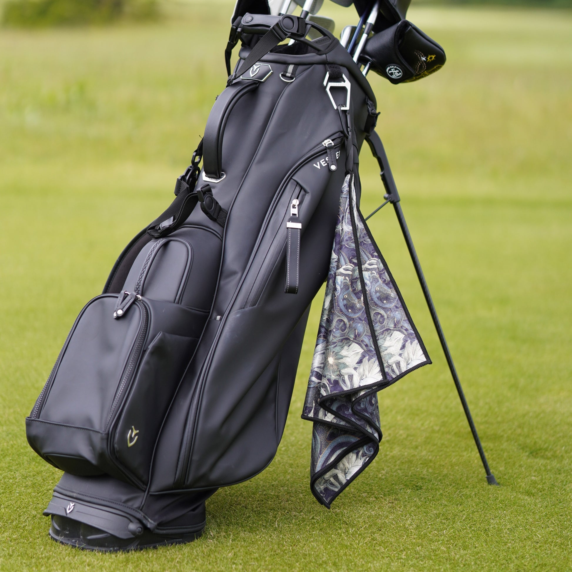 Black golf bag with golf clubs on a grassy background