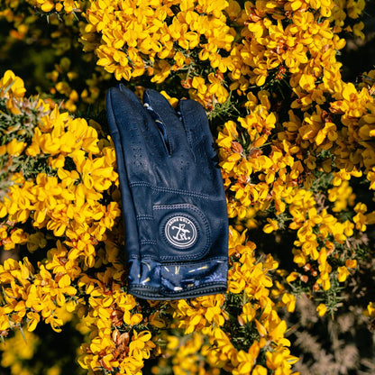 Navy blue leather golf glove with a logo on yellow flowers