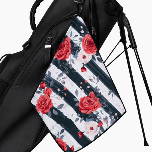 A black golf bag with a hanging rectangular towel featuring a red rose floral pattern over dark navy and white vertical stripes, shown on a clean white background.